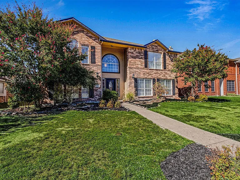 Brick and stone facade residence featuring a prominent arched window above the entry