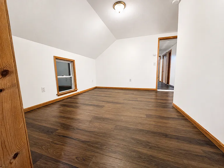 Spacious living area with warm wood-tone flooring and natural trim