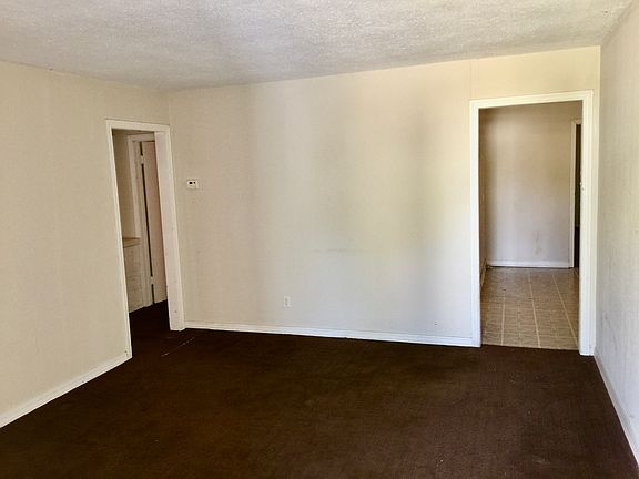 View Walking in Front Door into Living Room. Kitchen to right. Hallway to the 3 bedrooms on left.