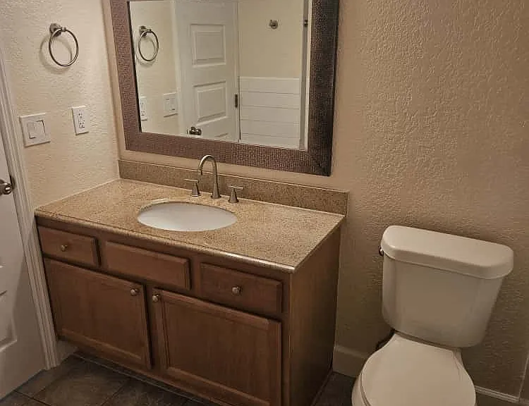 Bathroom featuring a wood vanity with granite countertop, updated lighting, and new fixtures.
