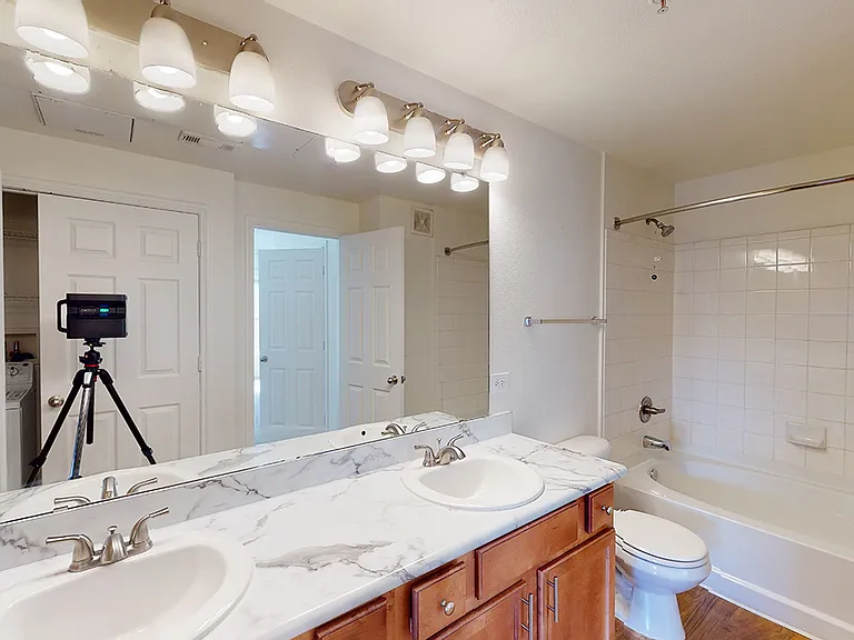Apartment bathroom with wood-style flooring and marble-style countertops (shown here). Quartz-style countertops are available in select homes.