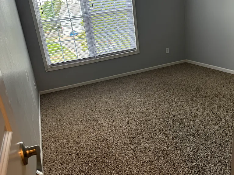 Bright secondary bedroom with soft carpeting, generous natural light, and versatile layout.