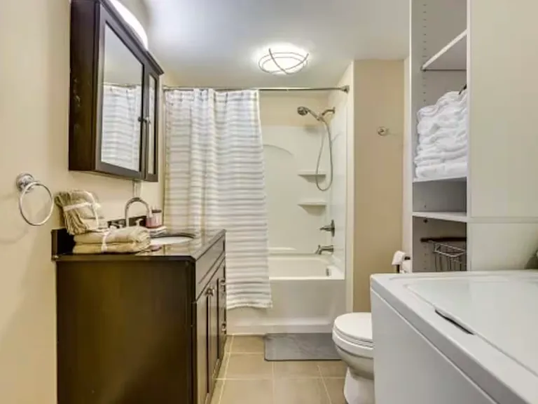Spacious master bathroom featuring a versatile handheld shower option for added convenience. Plenty of storage space available to neatly organize linens and towels, combining functionality with comfort.