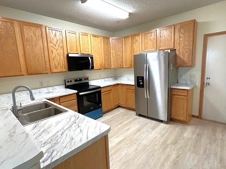 Kitchen view with new countertop and new appliances. door leads to garage. Walk in pantry not shown in this photo.