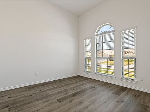 Room featuring a vaulted ceiling and wood-finish flooring