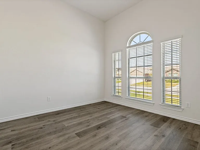 Room featuring a vaulted ceiling and wood-finish flooring