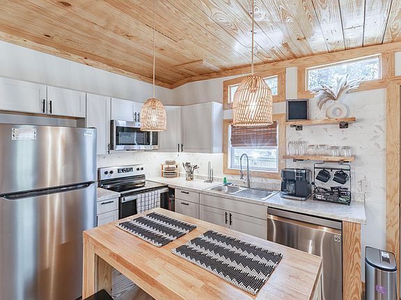 A quaint, brand-new modern kitchen boasts gleaming stainless steel appliances, efficient design, and complete functionality for convenient and stylish cooking.