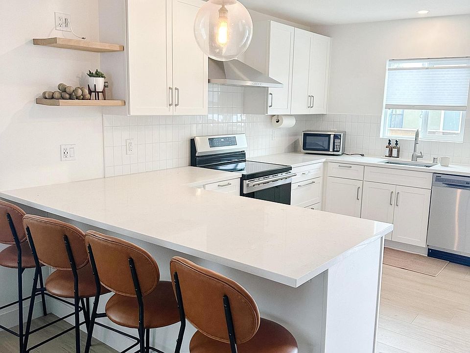 view of 4 bar stools and open concept kitchen.