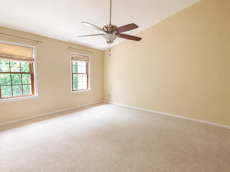 The primary suite features a cathedral ceiling, ceiling fan, two walk-in closets, and a renovated spa-inspired bathroom.