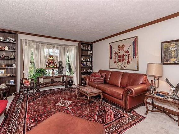 Spacious Living Room with Crown Molding, a Bay Window and Neutral Carpet