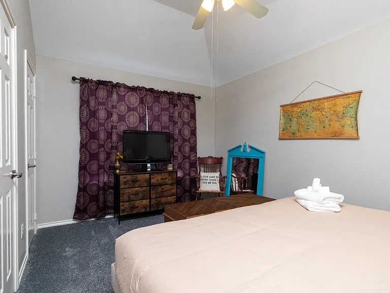 Bedroom 3 features soft neutral bedding, wall art, a TV, room-darkening curtains and a cozy atmosphere. Ideal for resting after a long day, with towels provided for your stay.