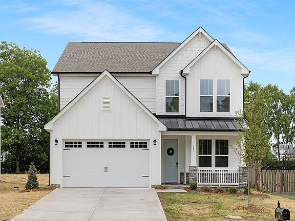 A white house with a black roof and a white garage door is for sale.