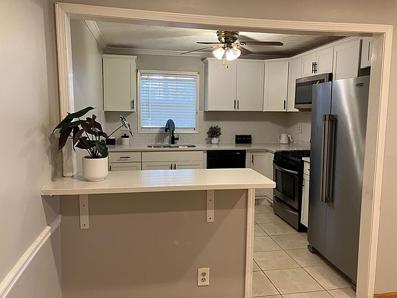 Renovated Kitchen with bar, quartz countertops, stainless steel refrigerator, stainless steel microwave, dishwasher, gas range with oven and garbage disposal.