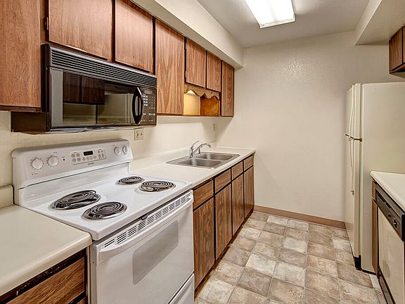 A kitchen with wood cabinetry and white appliances