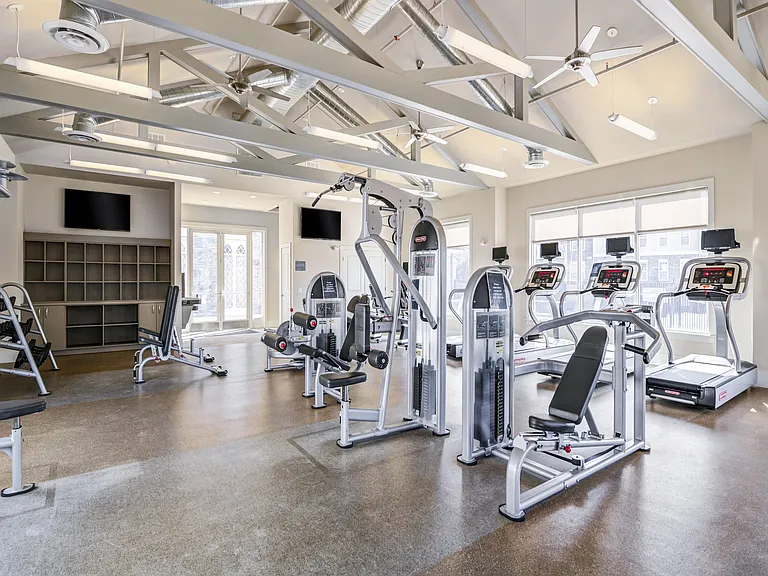 Modern fitness center featuring state-of-the-art gym equipment, including treadmills and weight machines, with bright natural lighting and sleek architectural design.