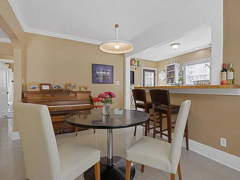 Dining room at Hunsucker's Place features a piano and a view into the kitchen. Located within walking distance of Cone Health Hospital and Downtown Greensboro, this space is perfect for enjoying meals and music in a cozy, central location.
