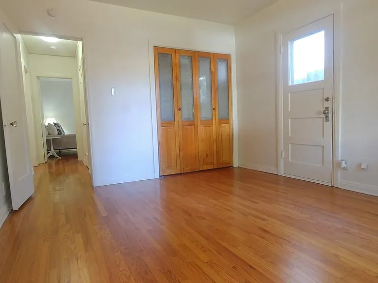 Large front bedroom with custom built closet and fresh wood floors.