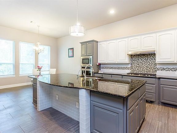 A spacious open-concept kitchen with a bar area for eating and space for a breakfast table. Hardware added to the cabinets 12/2020.