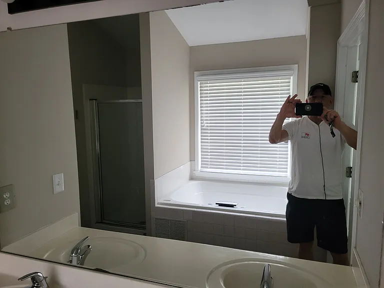 Bathroom with picture off of the mirror with some really bad photographer in it.