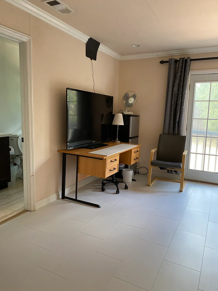 Furnished room has TV, antenna, desk, chairs, desk, fan. - Blandford Dr