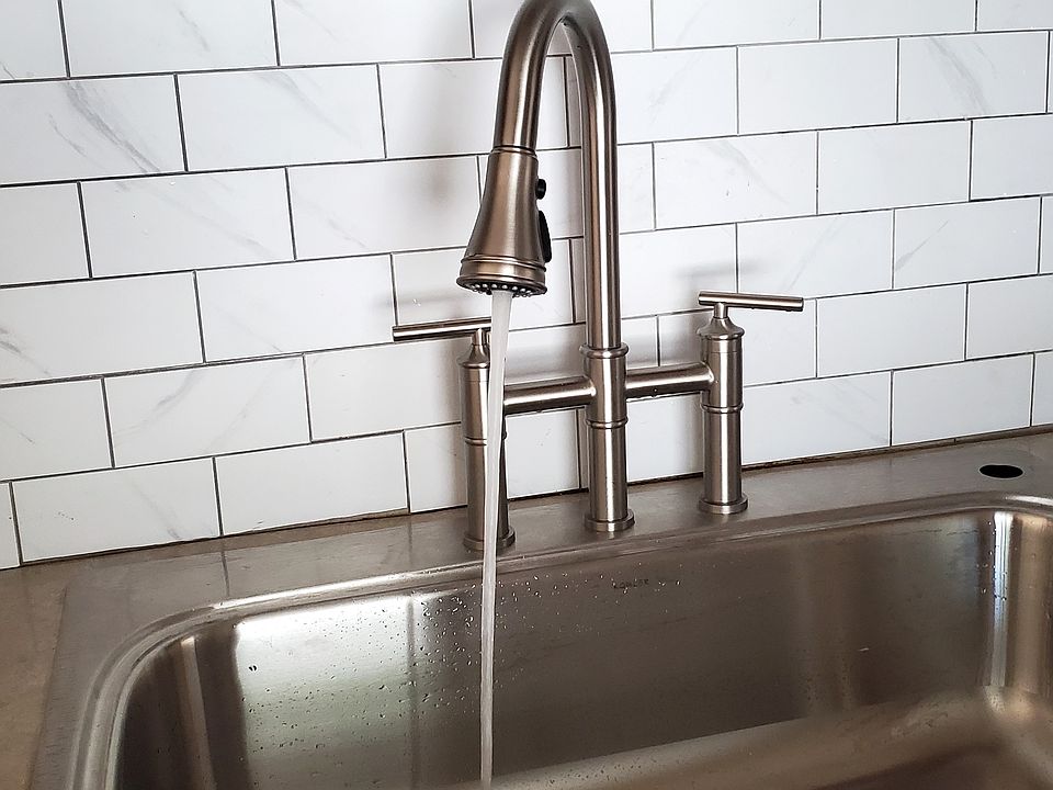 Bridge faucet and marble tile backsplash with deep sink.