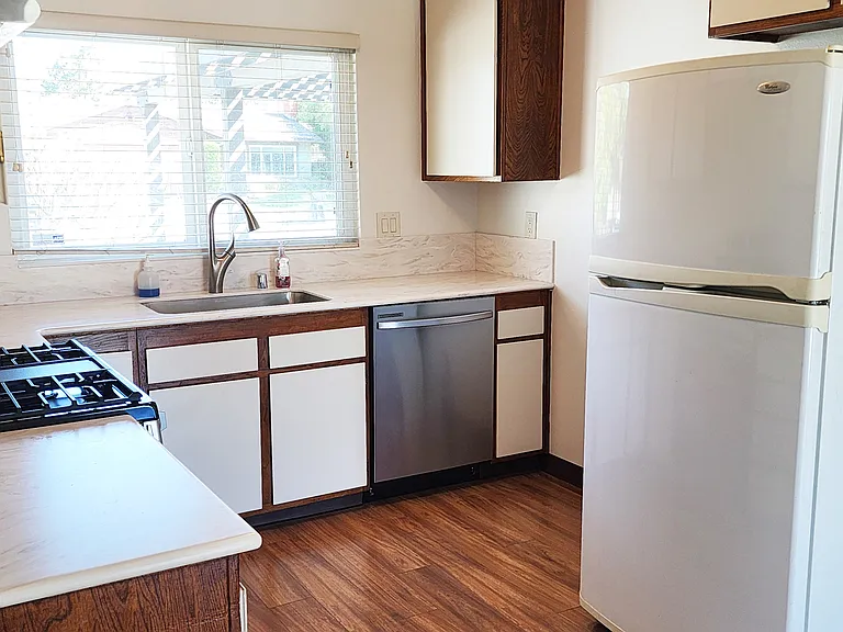 New kitchen counter top, gas oven and stove, overhead exhaust, sink and dishwasher.