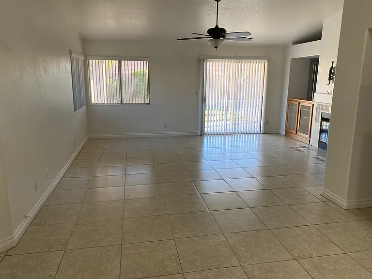 View of the family room from the kitchen. Backyard entry, ceiling fan, vaulted ceiling, dual-side gas fireplace. Custom cabinetry for TV and stereo equipment, TV mount above the fireplace. Built-in bookshelf to the right of the wall.