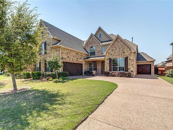 Brick & stone elevation with cedar garage doors and shutters, 3 car split bay garages, aggregate drive.