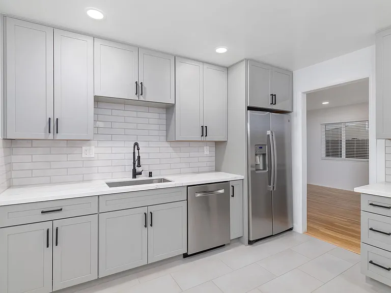 The fully remodeled kitchen features custom new cabinetry, elegant quartz countertops, and premium stainless steel appliances.