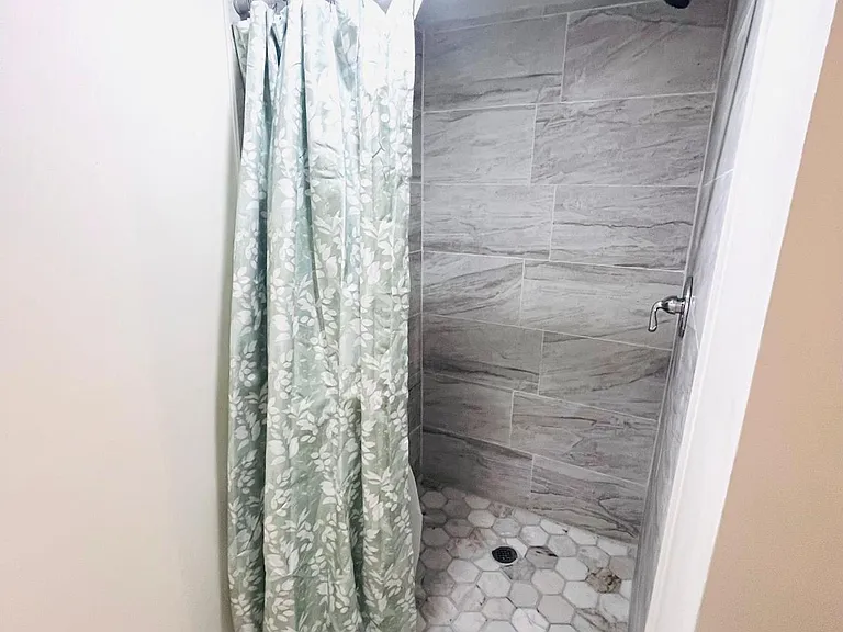 Walk-in shower with tile surround, hex-tile flooring, and a shower curtain for added privacy and easy upkeep.