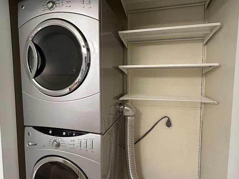 Built-in shelves next to the washer and dryer provide convenient extra storage for laundry essentials or household items.