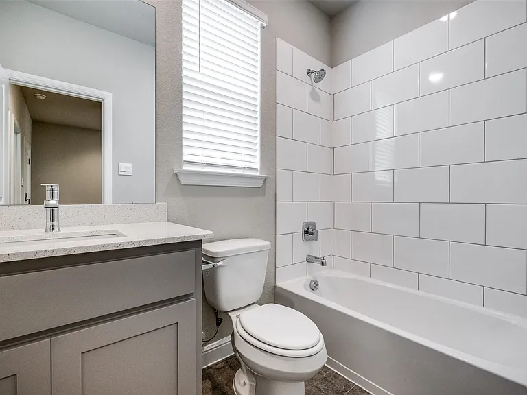 Full bathroom featuring oversized vanity, toilet, and tiled shower / bath combo