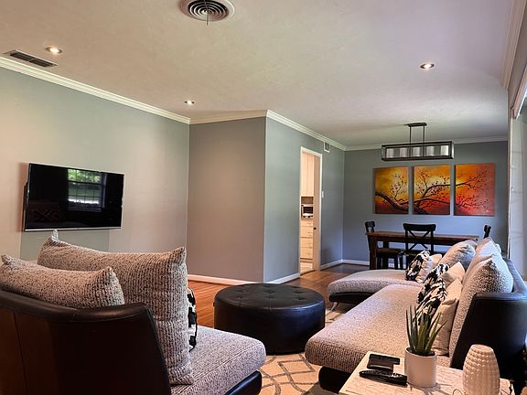 The generous living room layout offers plenty of wall space for entertainment setups and flexible furniture arrangements, accented by crown molding and a direct view into the kitchen entryway.