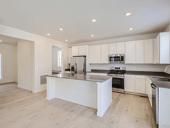 Kitchen with a large island, quartz countertops and stainless steel appliances including refrigerator