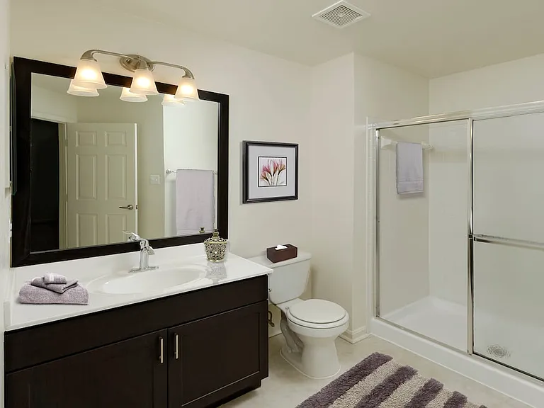 Renovated Package III bath with espresso cabinetry, white countertops, and vinyl tile flooring