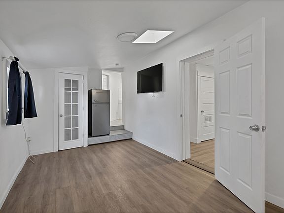 living room featuring a skylight, baseboards, and wood finished floors