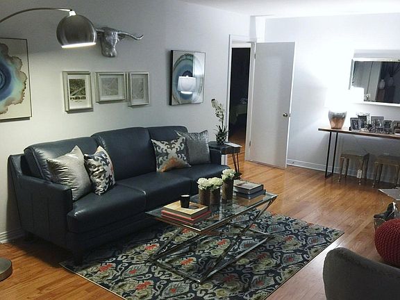 Living room with prior tenant furniture. Picture furnished by prior tenant. Door is entrance to back hallway for main bathroom and bedrooms.