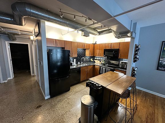 Kitchen area attached to living room. Original terrazzo floors and custom island unit built to match wood cabinets, desk, and shelving.