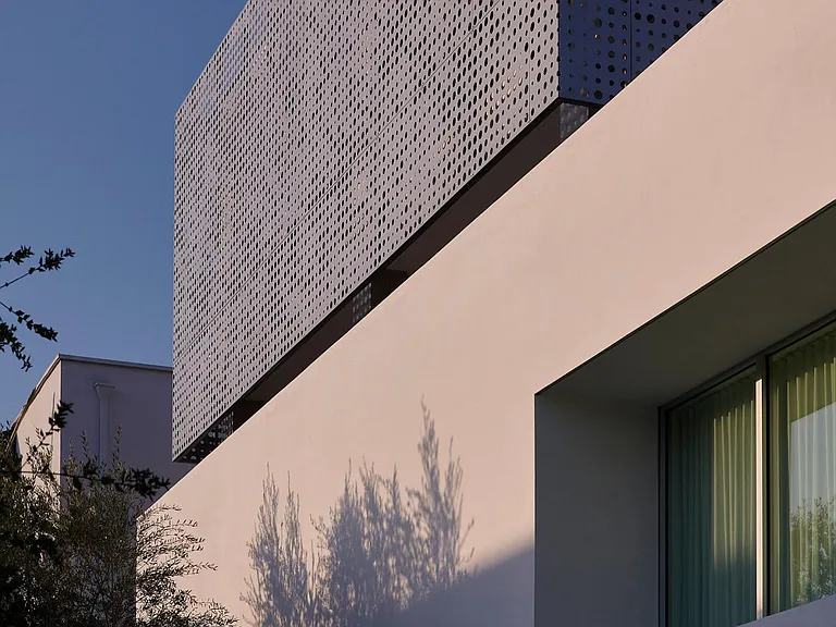 Perforated Stainless Steel Veil_ Crisp architectural lines and a subtle play of textures with the perforated stainless steel define the building's exterior, bringing together minimalist elegance with bold, sculptural form.