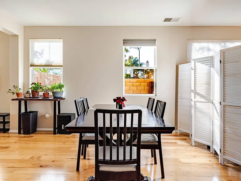 Dining area with a full-size table, seating for six, and multiple windows that bring in natural light.