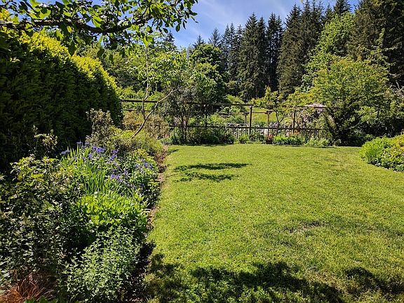 Lawn with fenced vegetable garden and view to field beyond.