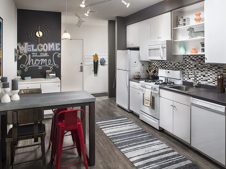 Classic Package I kitchen with white appliances, dark laminate countertops, white cabinetry, tile backsplash, and hard surface flooring