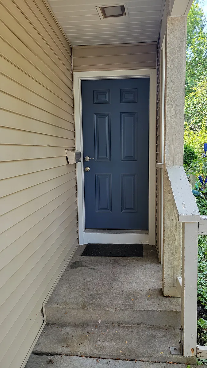 The front door is painted blue to add some color to the tan exterior. - 255 N Michigan St #99