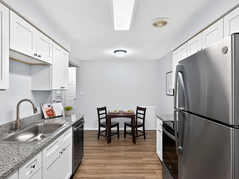 Modern kitchen with granite countertops, stainless steel appliances, and cozy dining area for two.