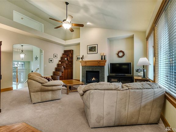 The main floor living room features vaulted ceilings, a gas fireplace, wood wrapped windows and is open to the kitchen and casual dining area.