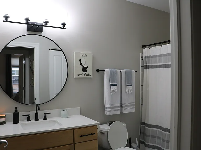 Updated bathroom featuring a stylish round mirror and chic vanity