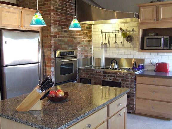Kitchen features stainless steel, brickwork, and quartz counters