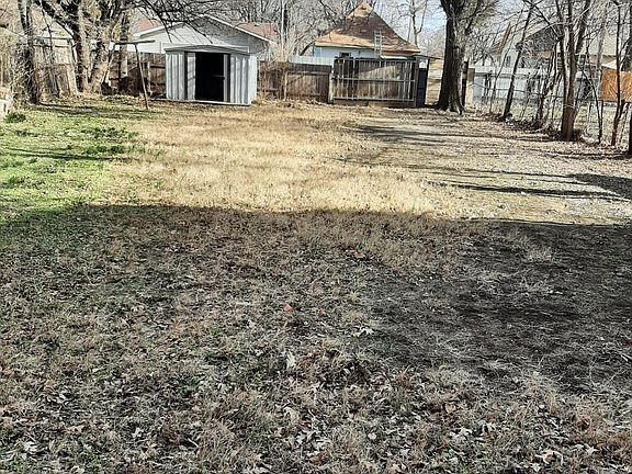 View of large fenced backyard looking toward back gate off alley; storage shed