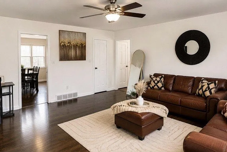 Spacious living room with hardwood floors, ceiling fan, and a comfortable seating area that flows into the dining space.
