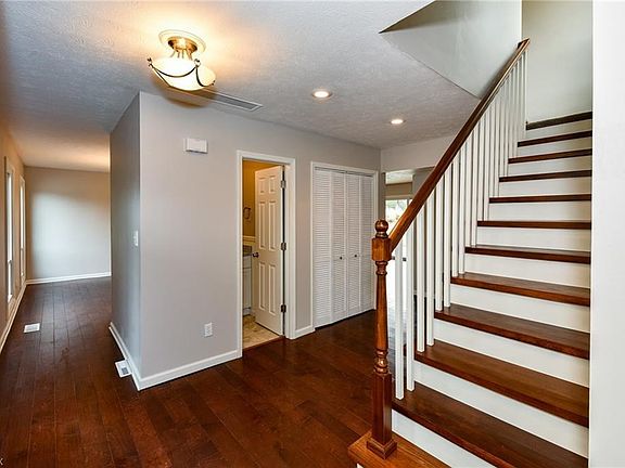 Pictured: Foyer entry with main staircase, great room entry (behind where photographer is standing), and 1st floor powder room. The left side of the photo leads you to the dining room, kitchen, hearth room, screened in porch, loft staircase, laundry, and 
